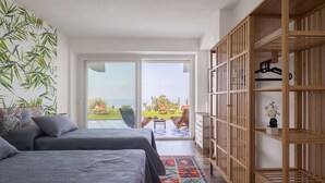 Ein Schlafzimmer mit zwei Betten, einem großen Fenster und Blick ins Freie.