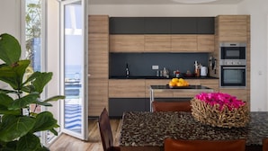 Eine moderne Küche mit Holzschränken, einer zentralen Kochinsel und einem Essbereich mit Tisch und Stühlen.