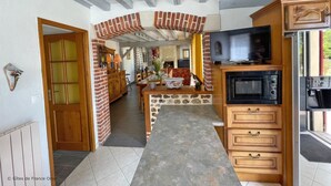 Een keuken met een televisie, oven en houten kastjes.