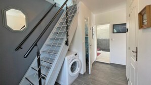 Een wasserij met een wasmachine, een droogrek en een trap met een leuning.