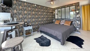 A modern bedroom with a large bed, a desk with a computer, and a chair.