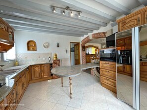 Een keuken met houten kasten, een centraal eiland, een inbouwoven en een magnetron.