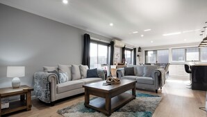A modern living room with a sofa, a coffee table, and a lamp. - Happy Tails Devonport (East Devonport)