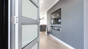 A hallway with a modern design, featuring a sliding glass door, a flat-screen TV mounted on the wall, and a ceiling fan. - Happy Tails Devonport (East Devonport)