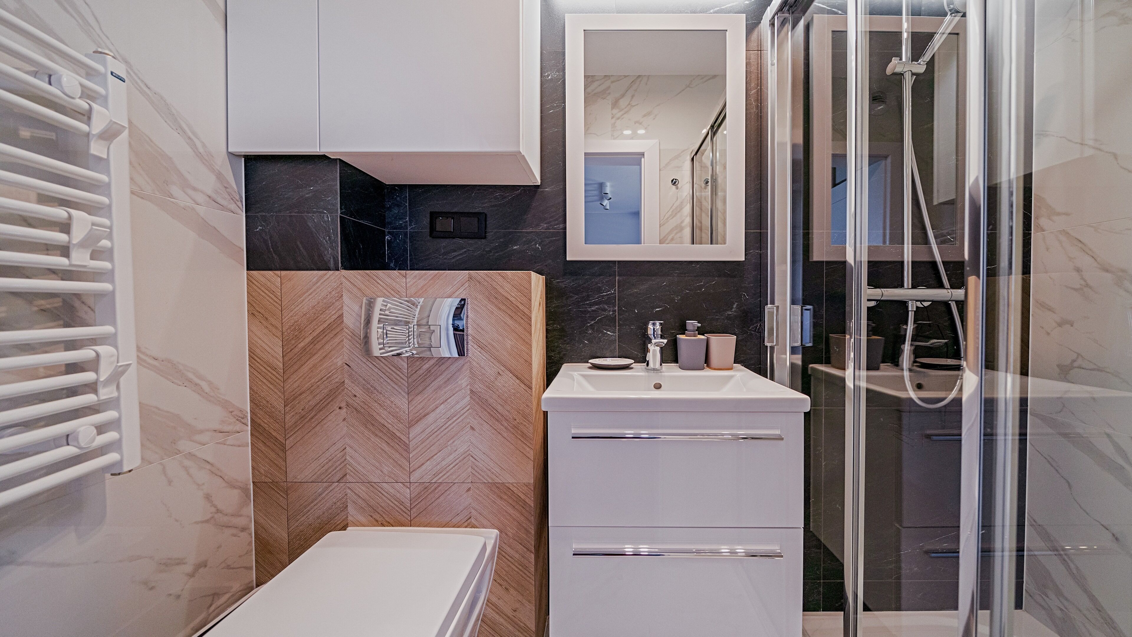 Een moderne badkamer met een douche, wastafel en toilet.