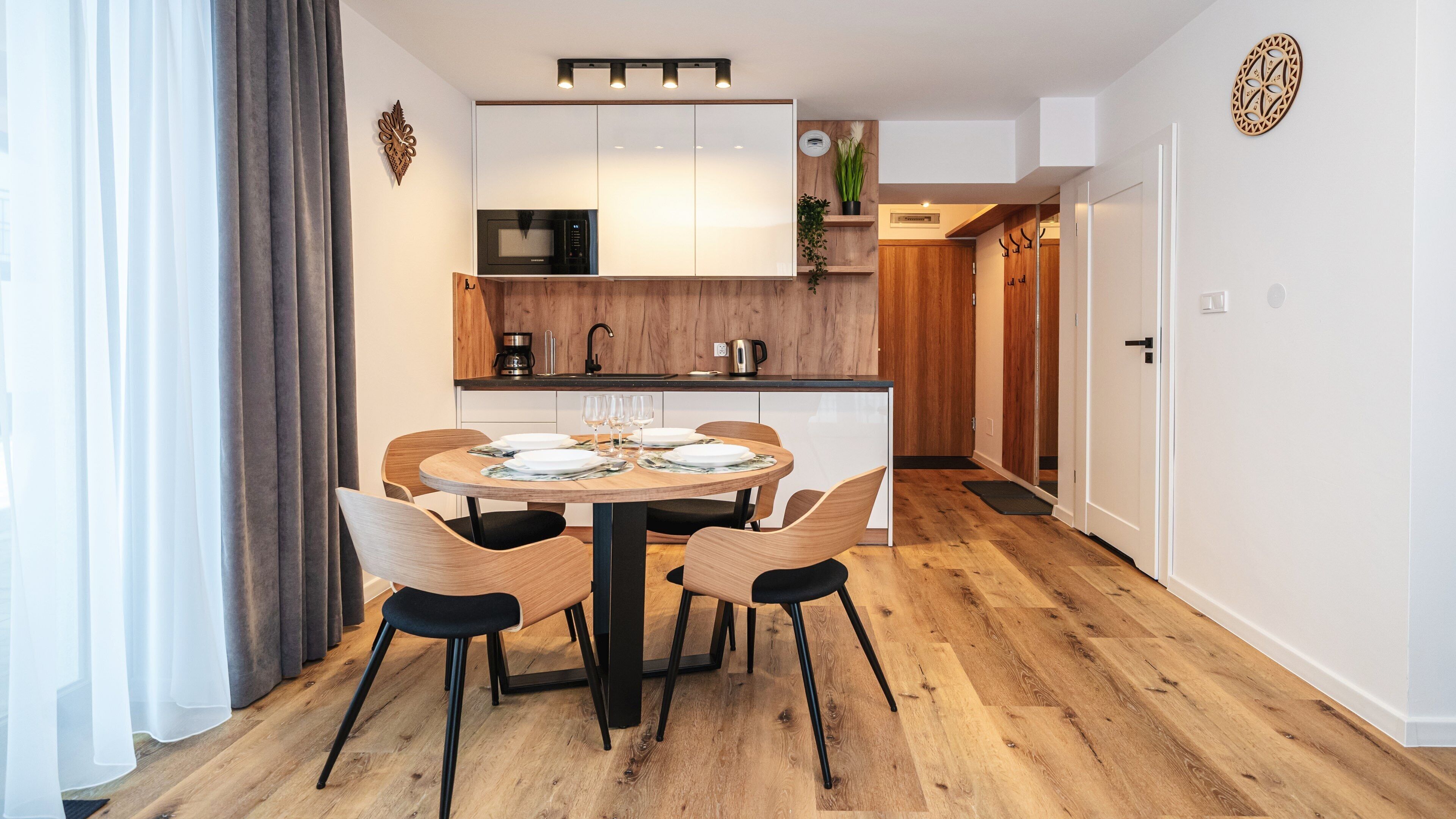 A modern kitchen with a central island, a dining table with chairs, and a microwave above the island.