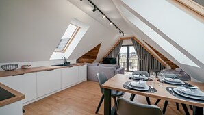 A modern kitchen with a skylight, a dining area with a table set for two, and a grey sofa.