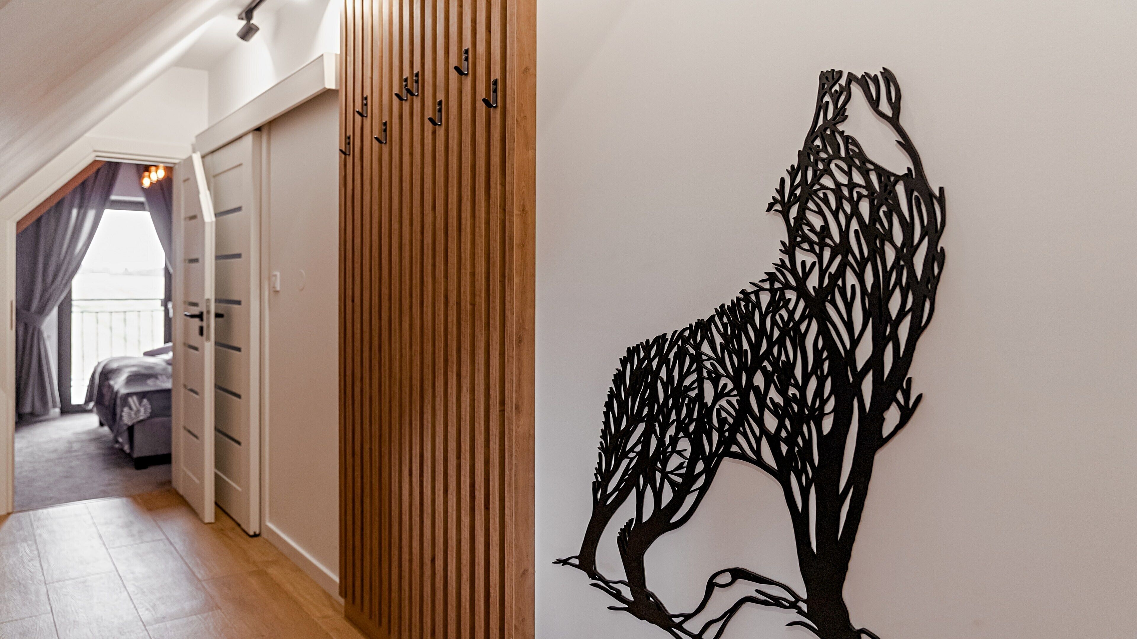 A hallway with a wooden panel wall, a bed, and a window with curtains.