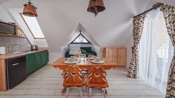 Una cocina compacta con comedor, un armario verde y una mesa de madera con sillas.
