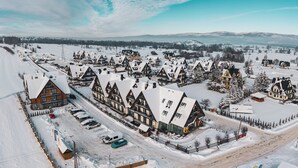 A snow-covered village with traditional chalet-style buildings, a main road, and a ski lift in the background.