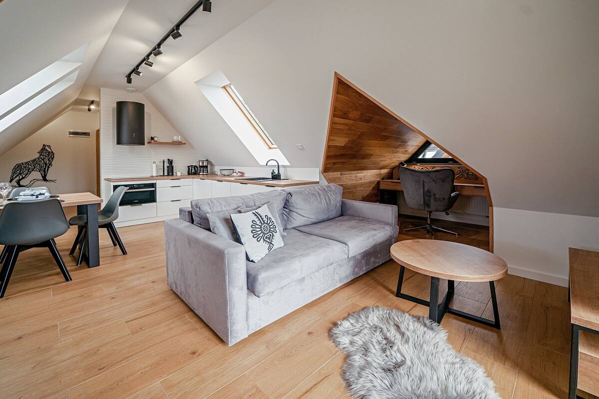 Um apartamento loft moderno com área de jantar, um sofá cinzento e uma mesa redonda pequena.