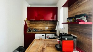 A compact kitchen with red cabinets, a wooden countertop, and a red appliance.