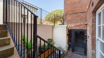 A courtyard with a brick building, a black door, and a staircase with metal railings.