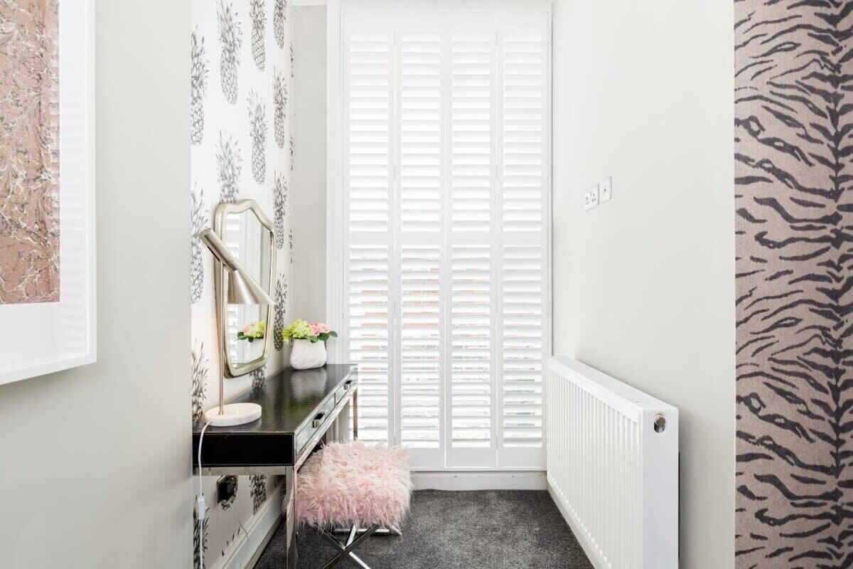 A bathroom with a vanity, mirror, and radiator.