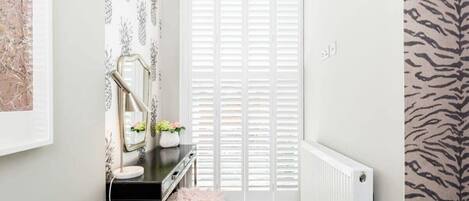A bathroom with a vanity, mirror, and radiator.