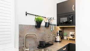 A modern kitchen with a stainless steel sink, a black utensil holder, and a kettle on the counter. - Ground floor compact studio with mini kitchen (Warrington)