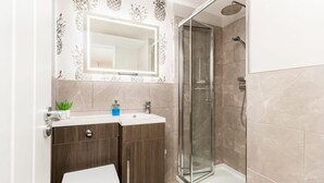 A bathroom with a toilet, vanity, and a glass-enclosed shower. - First floor compact studio with kitchenette (Warrington)