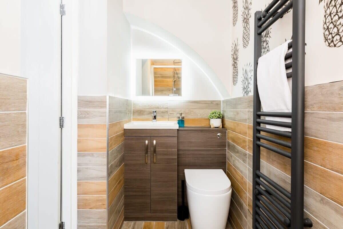 A compact bathroom with a modern design, featuring a sink, cabinet, toilet, and a towel rack.
