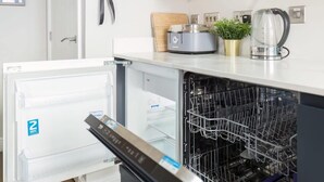 Eine moderne Küche mit integriertem Geschirrspüler und einem kompakten Kühlschrank.