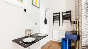 A compact kitchen with a black countertop, white walls, and a blue trash bin. - Second floor compact studio with mini kitchen (Warrington)