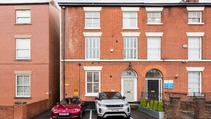 A two-story brick building with a number 70 sign above the door. - Second floor compact studio with mini kitchen (Warrington)