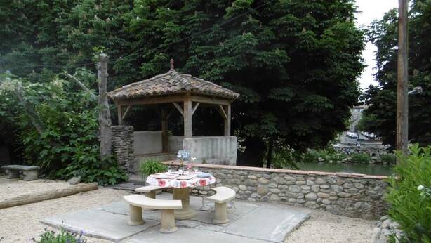 A gazebo with a tiled roof, surrounded by a stone wall and a gravel patio with a round table and benches. - Lovely Limoux: office, AC, kitchenette, WIFI, TV (Limoux)