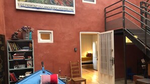 A cozy room with a blue bean bag, a bookshelf, a small table with a chair, and a staircase. - Lovely Limoux: office, AC, kitchenette, WIFI, TV (Limoux)