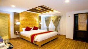 A modern hotel room with a wooden floor, a large bed with red pillows, a TV, and a wooden ceiling. - MeroStay 187 Hotel KM (Kathmandu)
