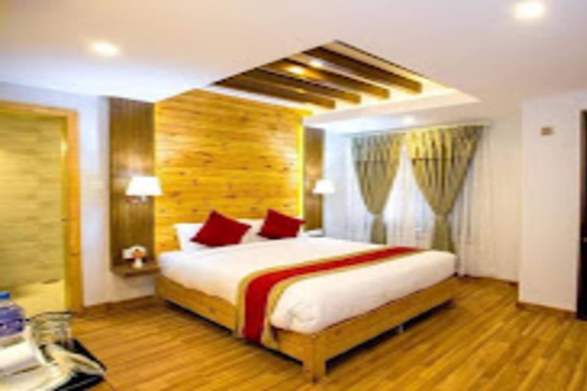 Een moderne hotelkamer met een houten vloer, een groot bed met rode kussens, een televisie en een houten plafond.