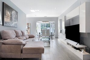 Una sala de estar moderna con un sofá, un televisor de pantalla plana y una mesa de comedor de vidrio.