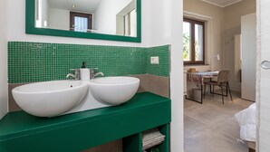 Ein Badezimmer mit zwei weißen Waschbecken, einer grün gefliesten Wand und einem Spiegel darüber.