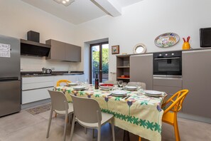 Eine moderne Küche mit Essbereich, ausgestattet mit Kühlschrank, Backofen und einem Esstisch für vier Personen.