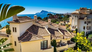 A coastal residential area with terracotta-tiled buildings, a clear blue sky, and a distant mountain. - 'Gadea 6-2' Apartment with Sea Views, Wi-Fi, and Air Conditioning (Altea)
