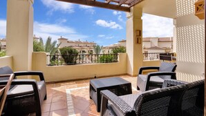 A covered outdoor seating area with wicker furniture, a tiled floor, and a view of buildings in the background. - 'Gadea 6-2' Apartment with Sea Views, Wi-Fi, and Air Conditioning (Altea)