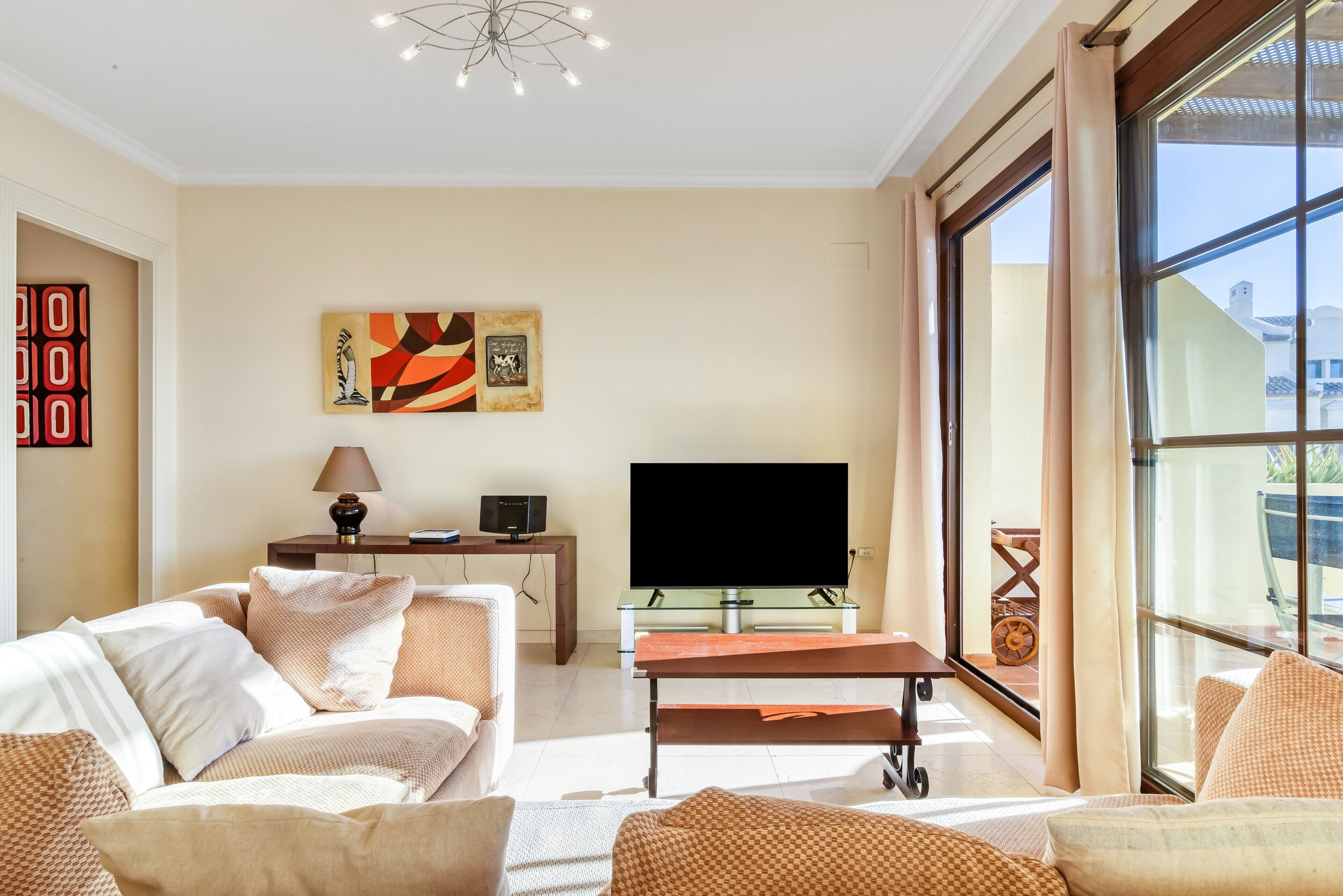 A living room with a sofa, a coffee table, a flat-screen TV, and artwork on the wall.