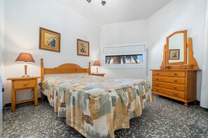 Ein Schlafzimmer mit einem Bett, zwei Nachttischen, einer Kommode, einem Spiegel und zwei gerahmten Bildern an der Wand.
