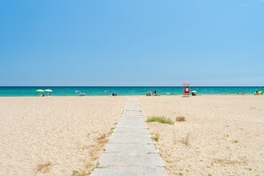 A beach with a clear path leading to the water, a lifeguard tower, and umbrellas. - Apartment 'Edificio Victoria 1º-1ª' with Sea View, Private Terrace and Wi-Fi (Sant Salvador (El Vendrell))