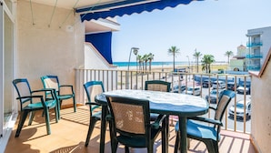 A balcony with a table and chairs, overlooking a beach and parking area. - Apartment 'Edificio Victoria 1º-1ª' with Sea View, Private Terrace and Wi-Fi (Sant Salvador (El Vendrell))