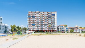 Ein mehrstöckiges Hotel mit Balkonen direkt am Strand, bewölkter Himmel.