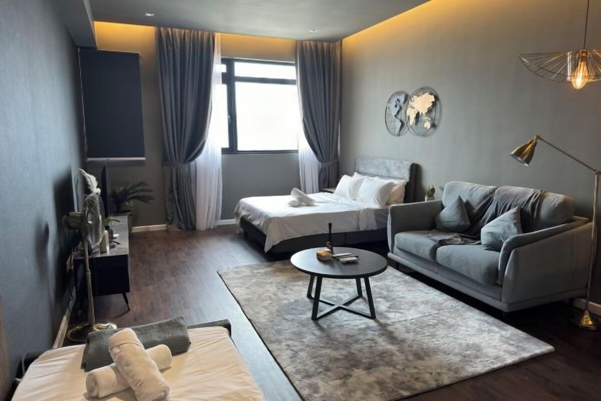 A modern hotel room with a bed, a sofa, a coffee table, and a desk.