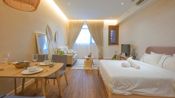 A hotel room with a bed, a desk, a chair, a dining table set for two, and a television. - Chambers PWTC By Unimax (Kuala Lumpur)