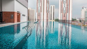 A swimming pool with a tiled floor, surrounded by a metal fence, and tall residential buildings in the background. - Chambers PWTC By Unimax (Kuala Lumpur)