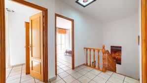 Un couloir avec une porte en bois, un escalier avec une rampe en bois et un tableau accroché au mur.