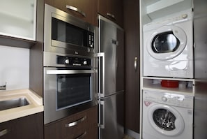 Een compacte keuken met een ingebouwde oven, magnetron en een wasmachine.