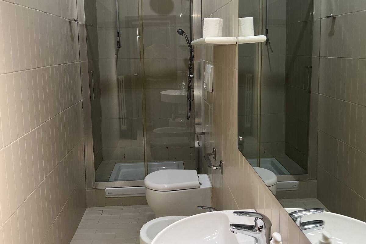 Un baño moderno con cabina de ducha de vidrio, inodoro y lavamanos grande.