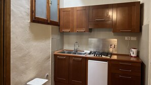 Une cuisine de taille réduite, dotée de meubles de rangement en bois, d’un évier, d’une cuisinière et d’un réfrigérateur.