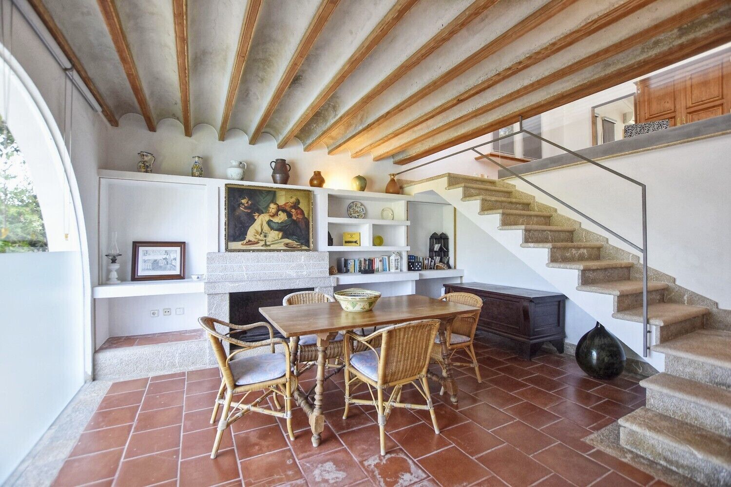 A dining area with a table and chairs, a fireplace, and a staircase.