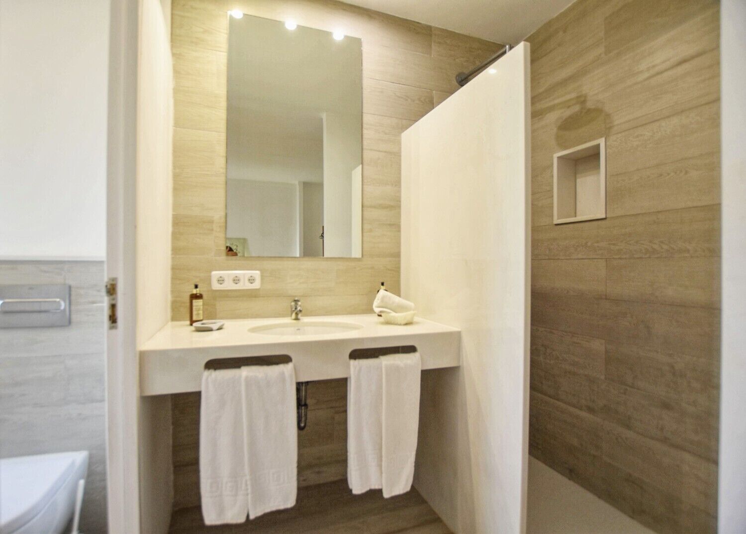 Une salle de bain dotée d’un grand miroir, de deux lavabos et d’un espace douche.