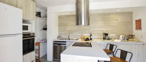 A modern kitchen with a central island, built-in appliances, and a stainless steel range hood.