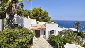 A coastal property with a white exterior, a tiled roof, and a view of the sea.